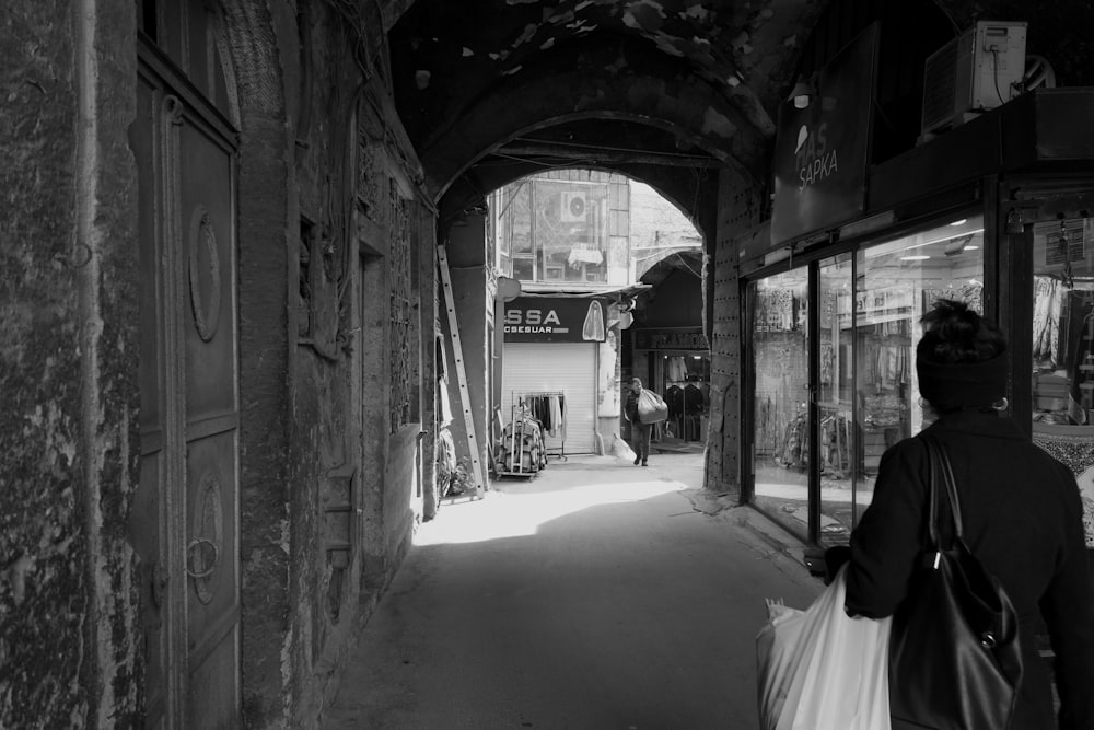 a black and white photo of a person walking down a street