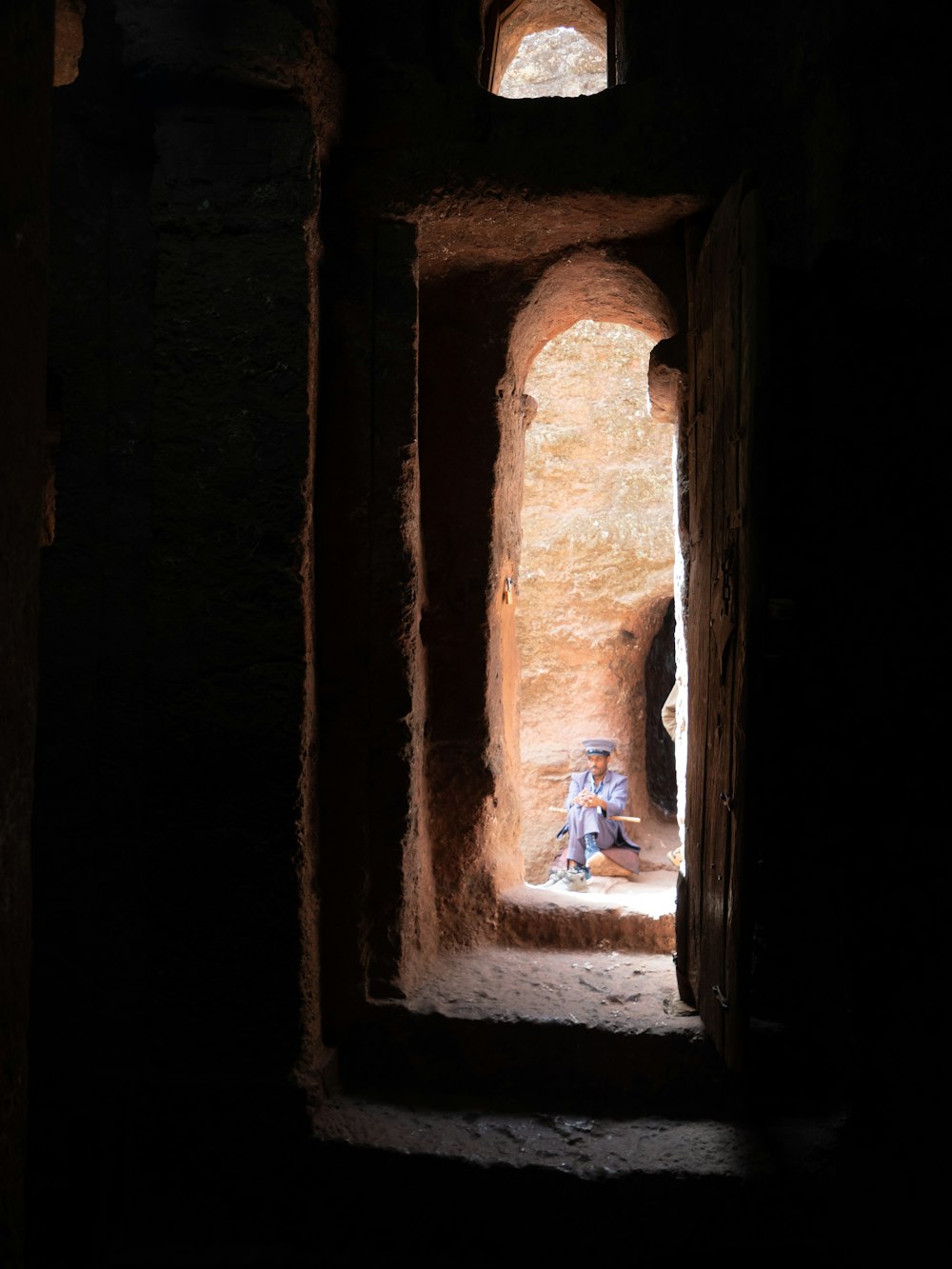 a man sitting in a doorway of a stone building