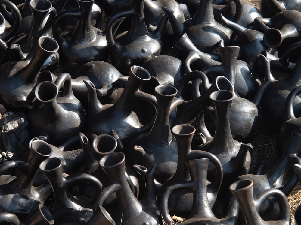 a pile of black vases sitting next to each other