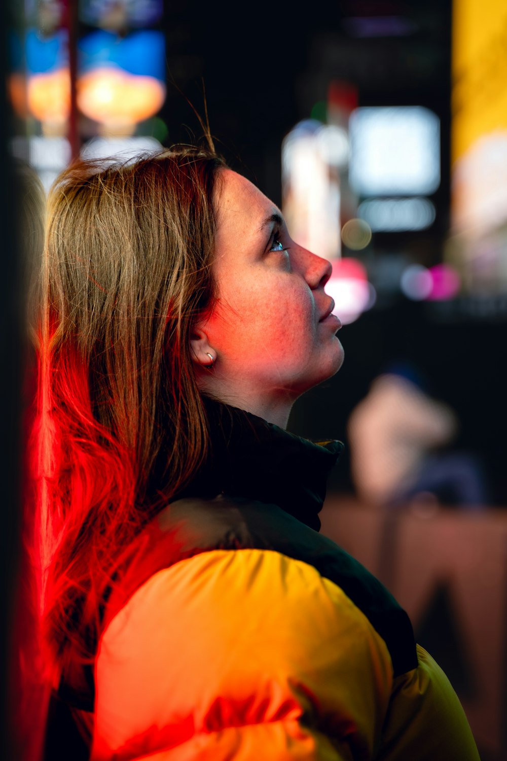 a woman in a yellow and black jacket looking up