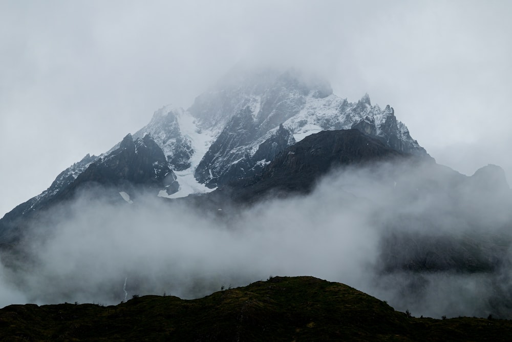 a mountain covered in clouds and snow on a cloudy day