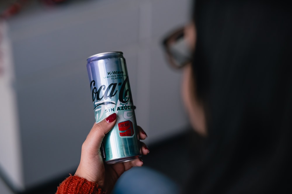 a woman holding a can of coca cola