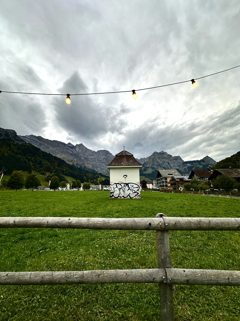 a field with a fence and a building with graffiti on it