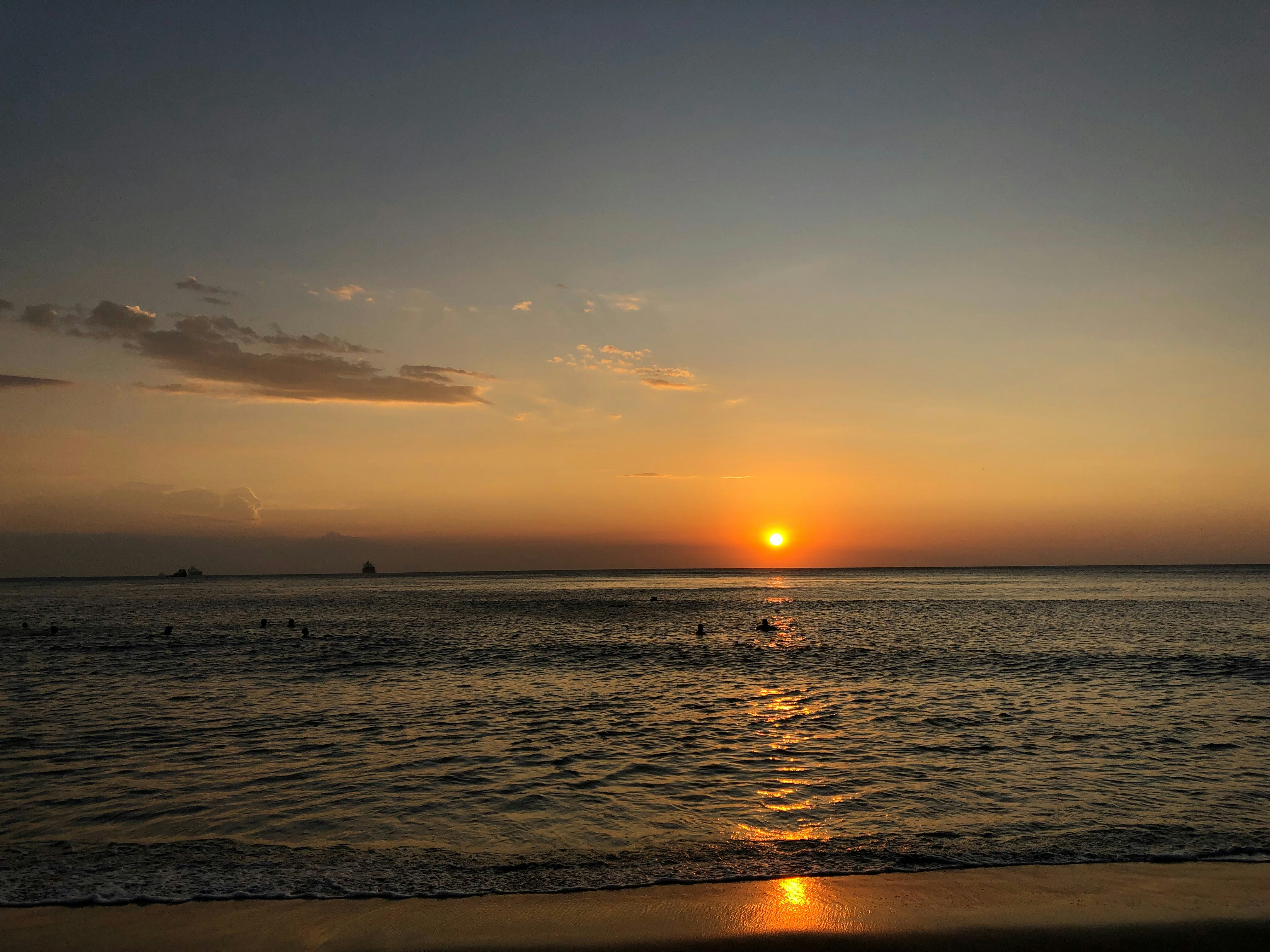 the sun is setting over the water at the beach