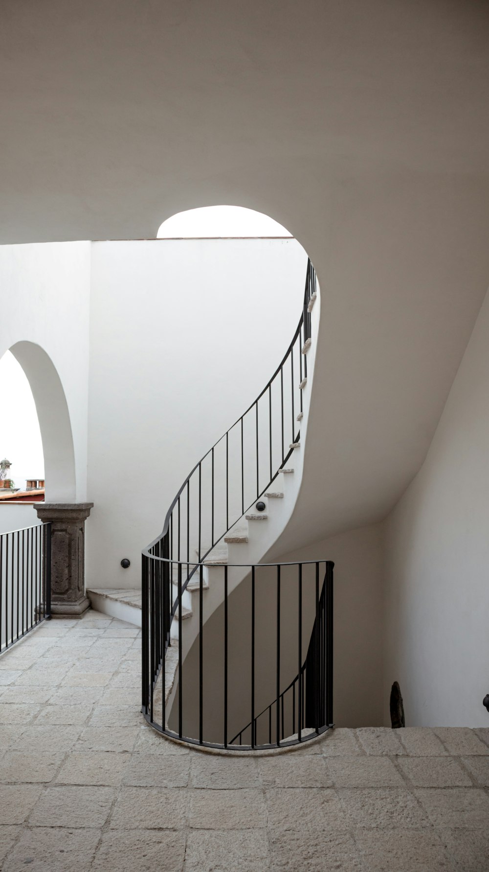 a spiral staircase in a white building with a black railing