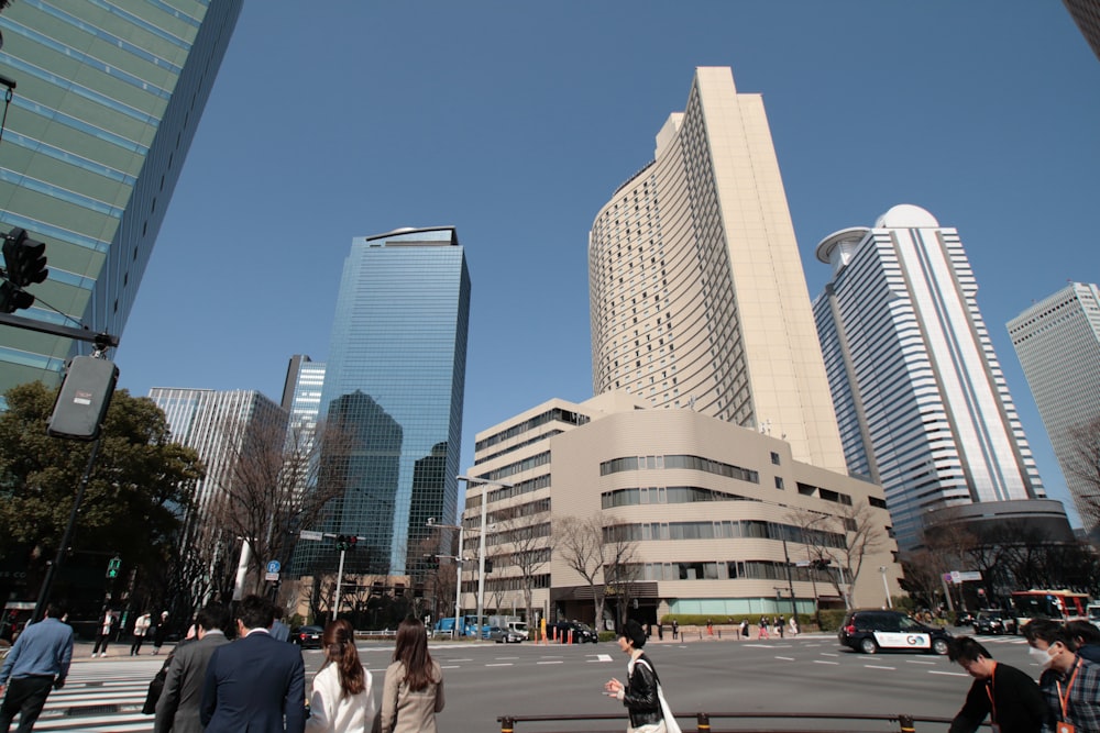 a group of people walking across a street next to tall buildings