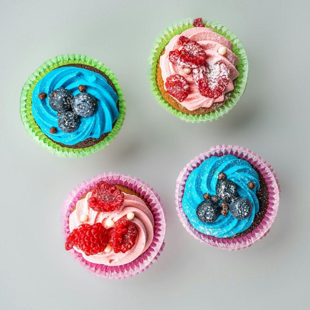 three cupcakes with blue, pink and red frosting