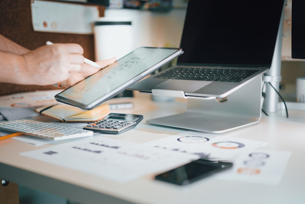 a laptop computer sitting on top of a desk next to a calculator