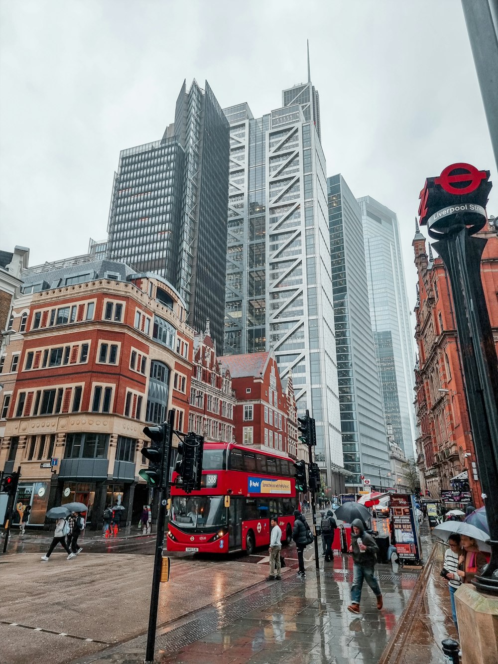 a red double decker bus driving past tall buildings