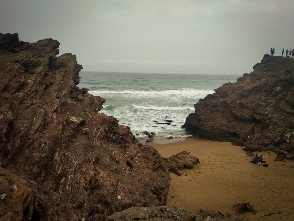 a group of people standing on top of a cliff next to the ocean