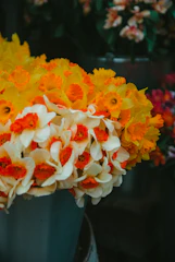 a bucket filled with lots of yellow and orange flowers