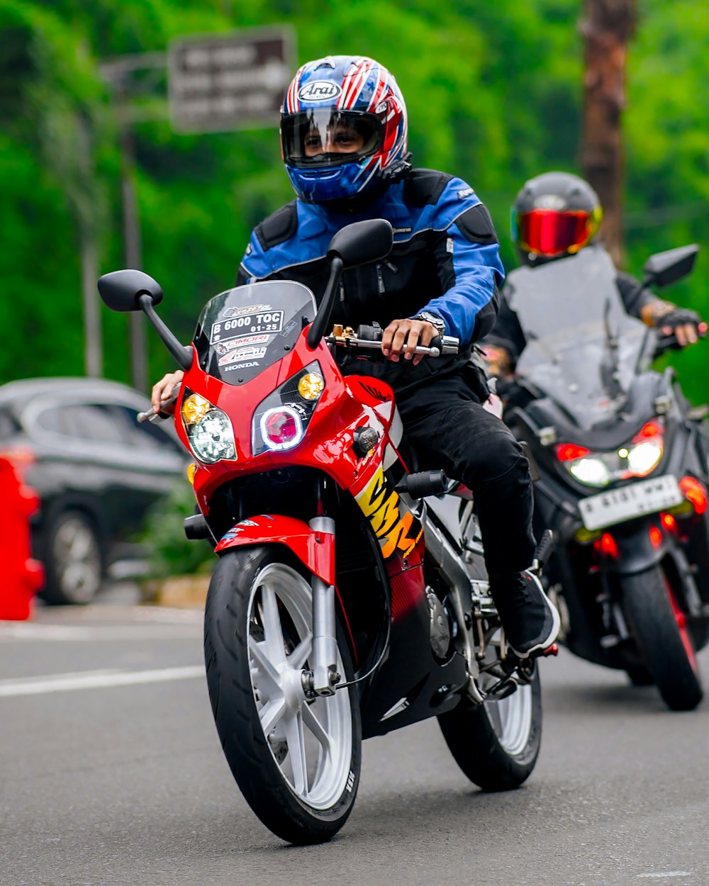 a man riding a red motorcycle down a street