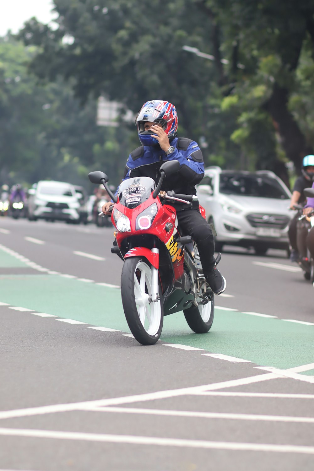 a man riding a red motorcycle down a street