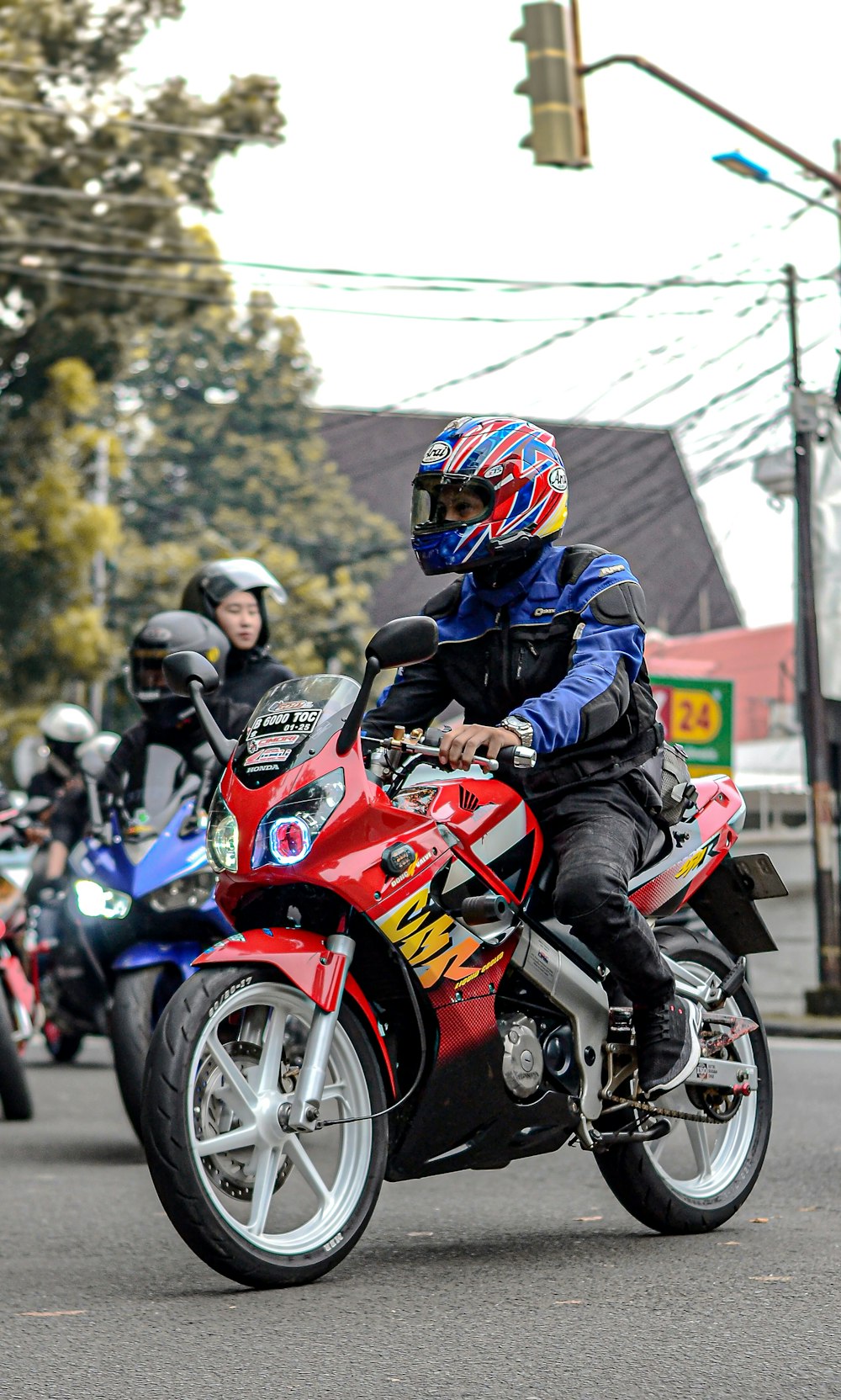 um homem pilotando uma motocicleta vermelha em uma rua