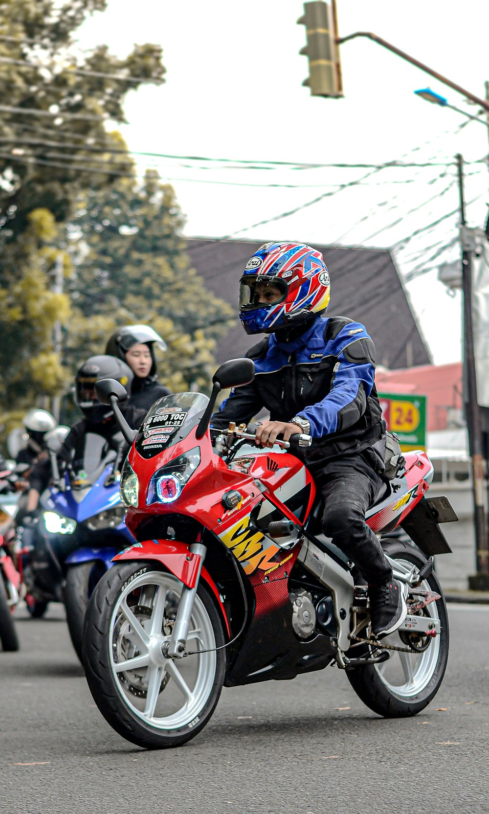 a man riding a red motorcycle down a street