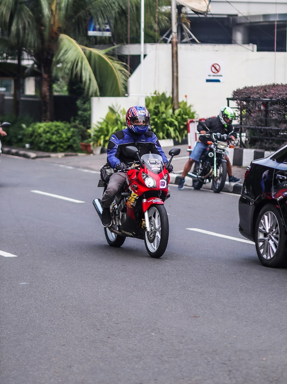 a man riding a red motorcycle down a street