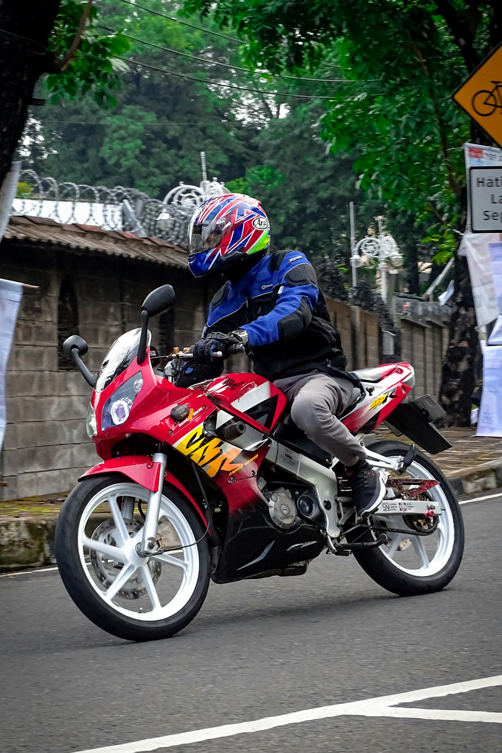 a man riding a red motorcycle down a street