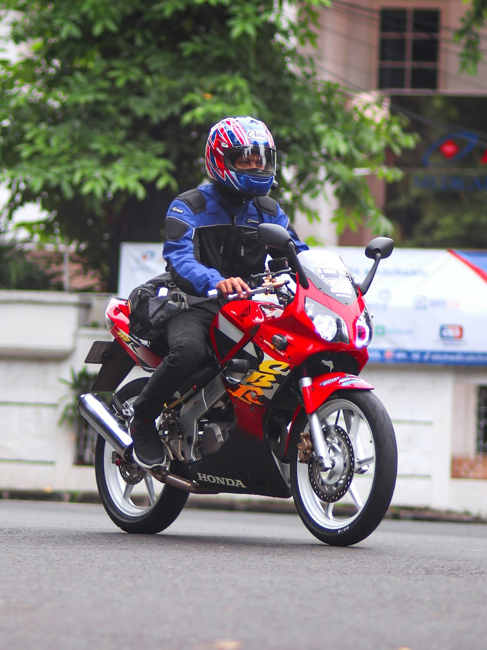 a man riding a red motorcycle down a street