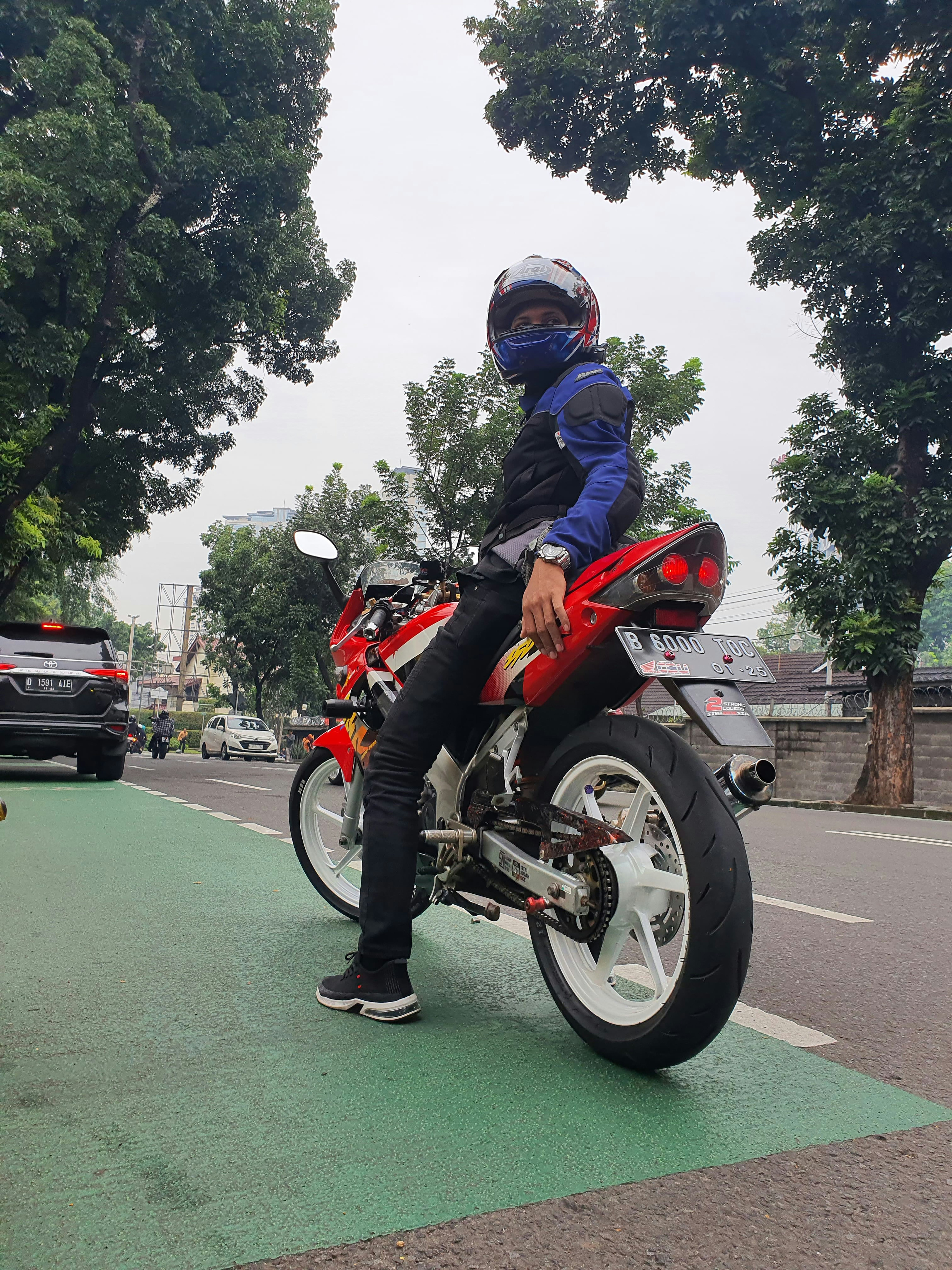 a man sitting on a red motorcycle on a city street