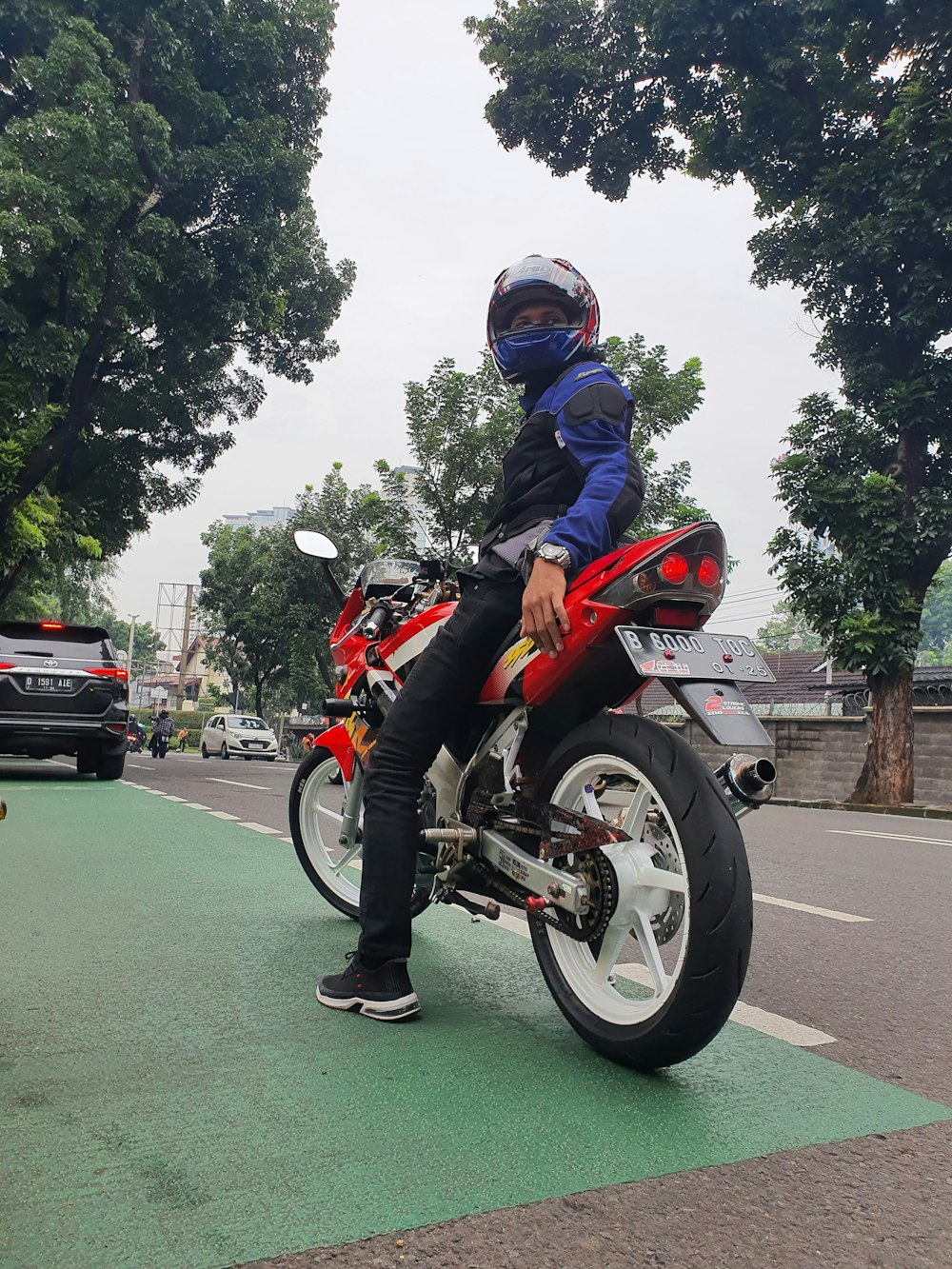 도시 거리에서 빨간 오토바이에 앉아있는 남자