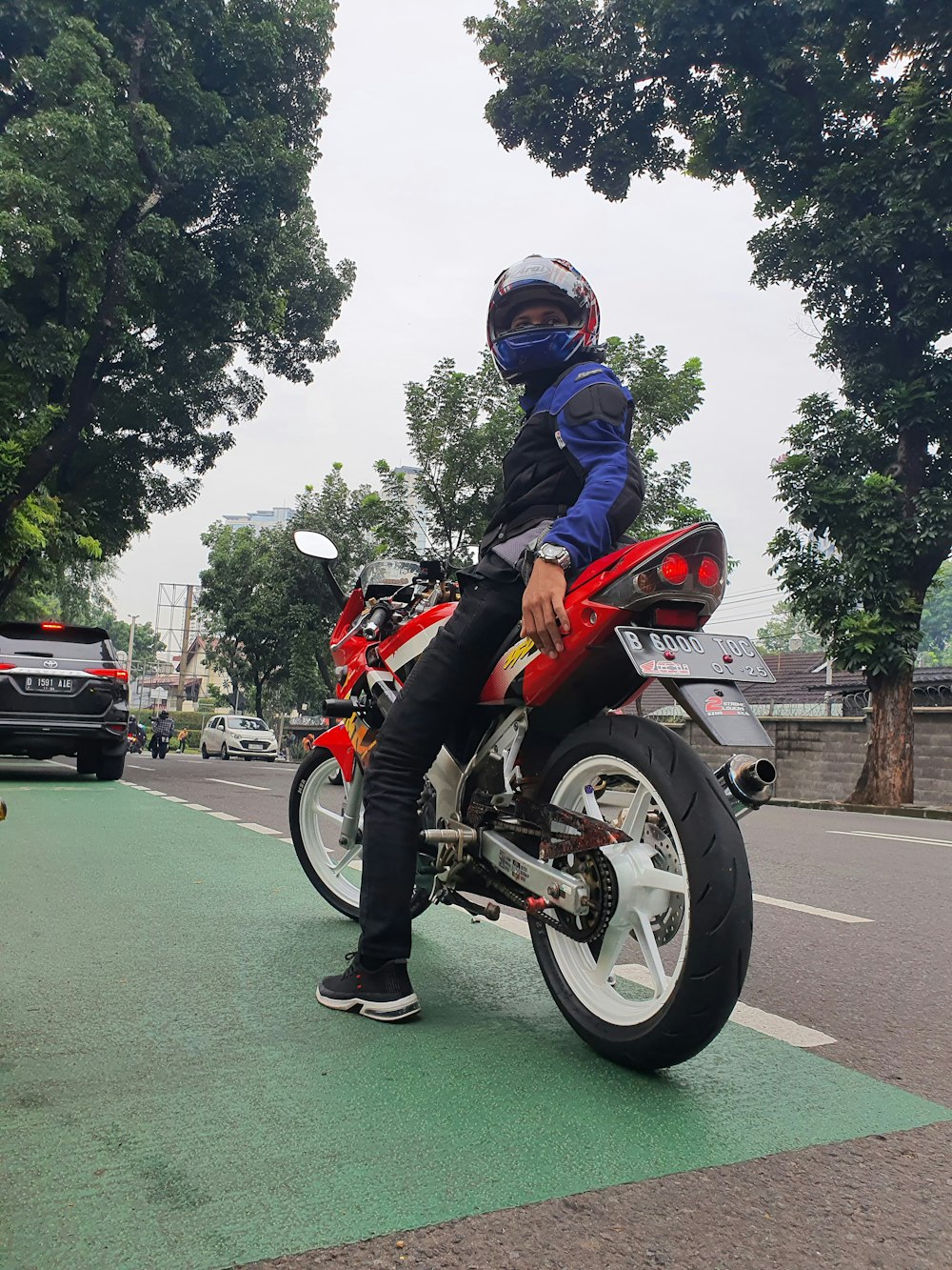 a man sitting on a red motorcycle on a city street