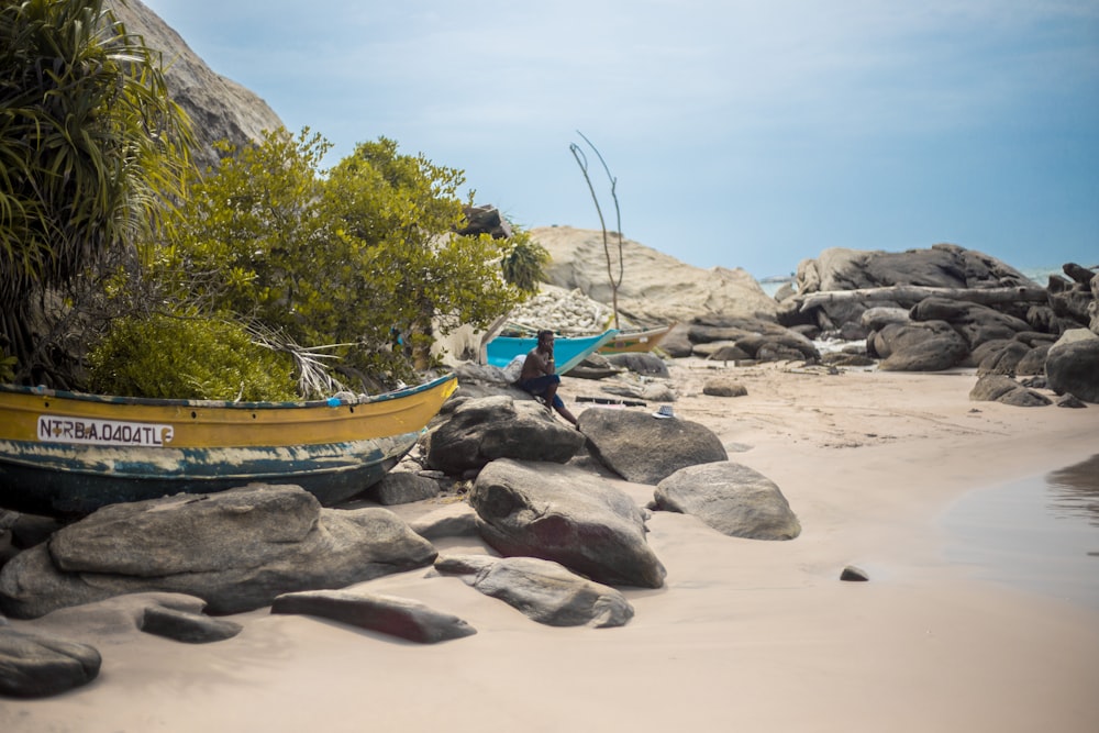 a boat on a beach with rocks and plants