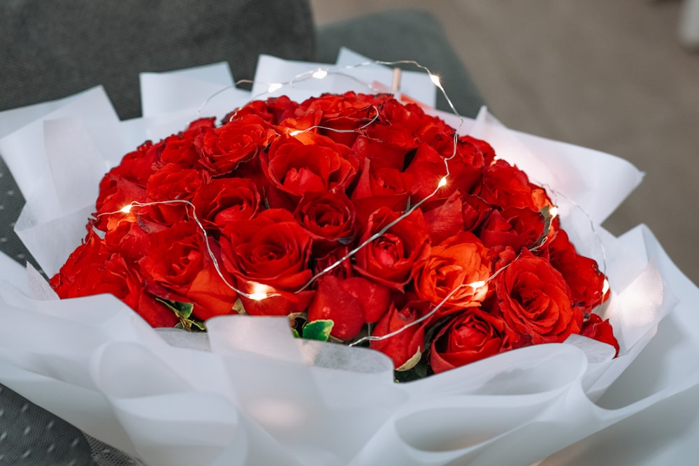 a bouquet of red roses with a string of lights