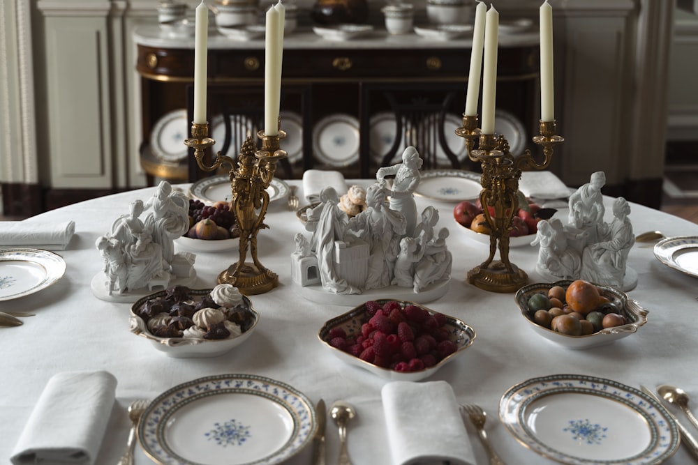 a white table topped with plates and candles