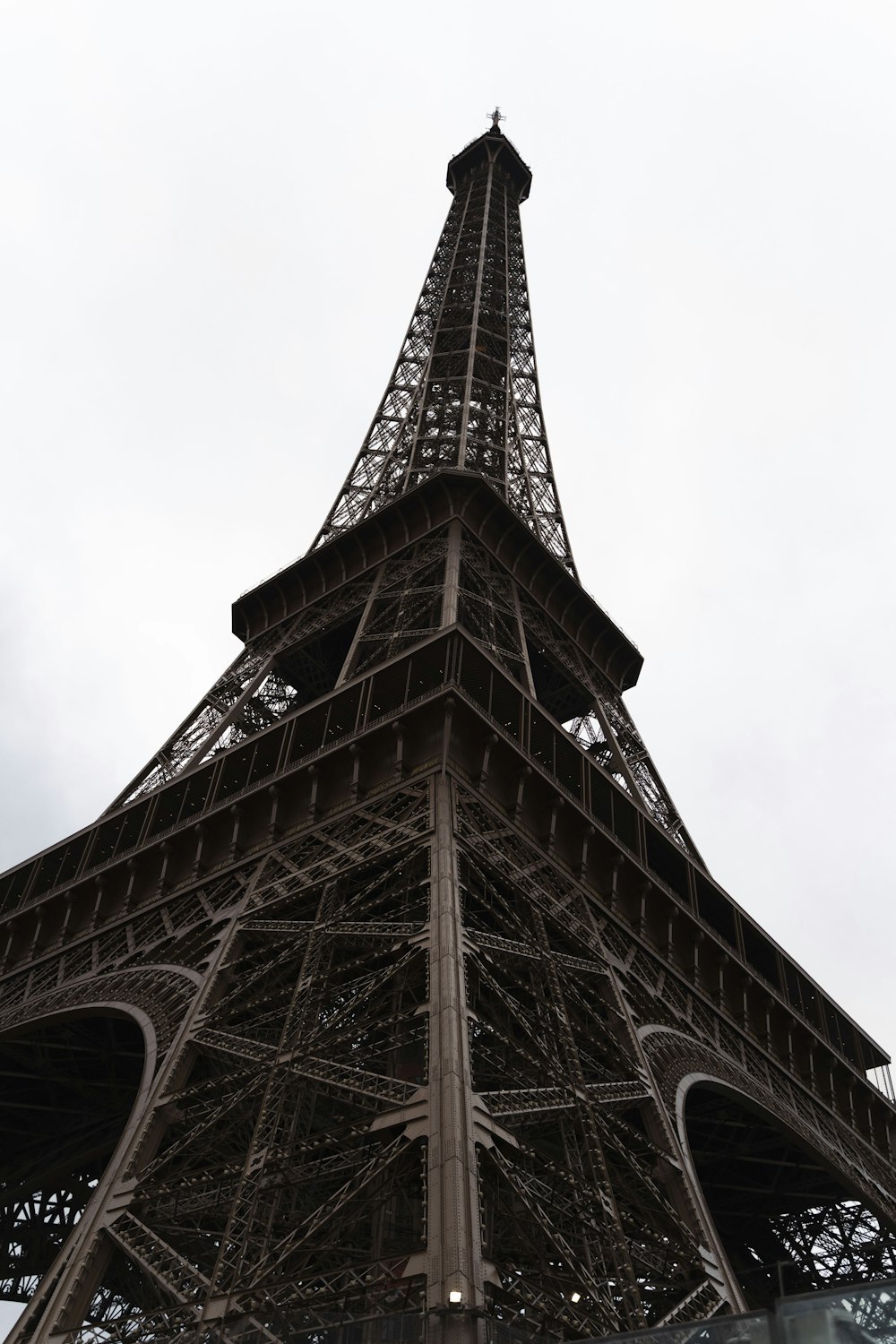 the top of the eiffel tower against a cloudy sky