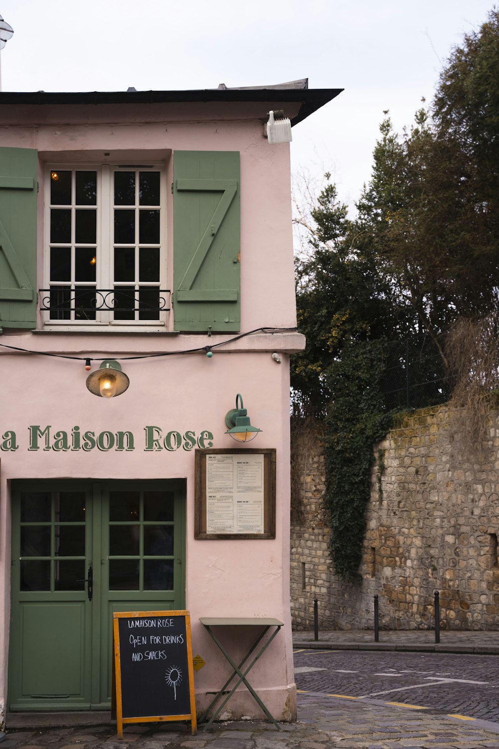 a pink building with a green door and window