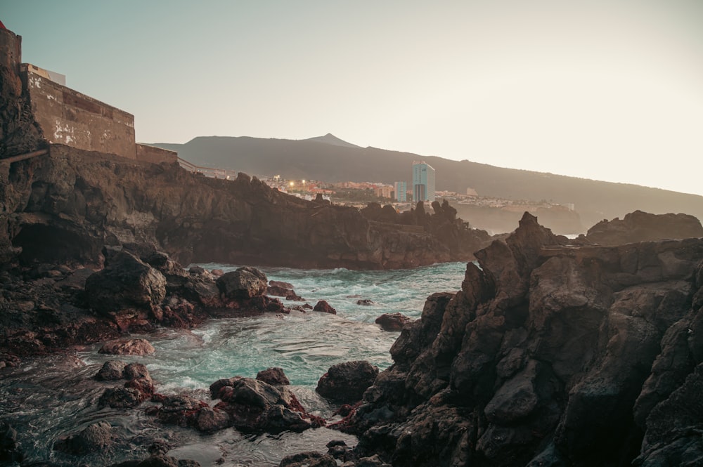 a view of a rocky coastline with a city in the distance