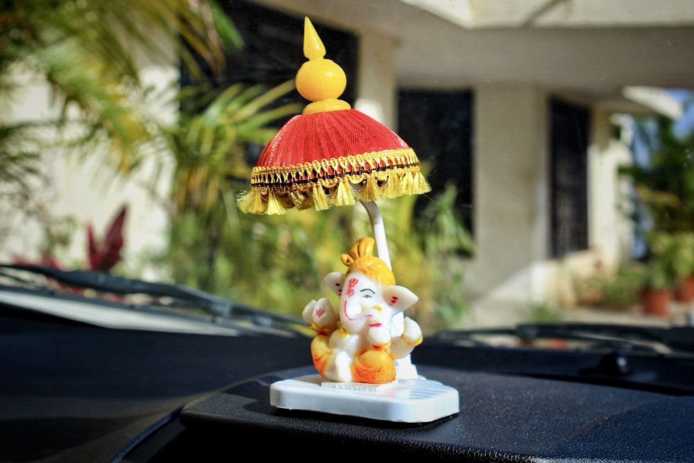 una piccola statua di un elefante che tiene in mano una lampada sul tetto di un'auto