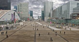 a group of people walking around a plaza in a city