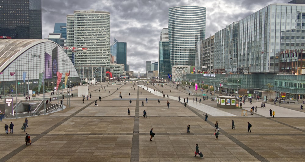 a group of people walking around a plaza in a city