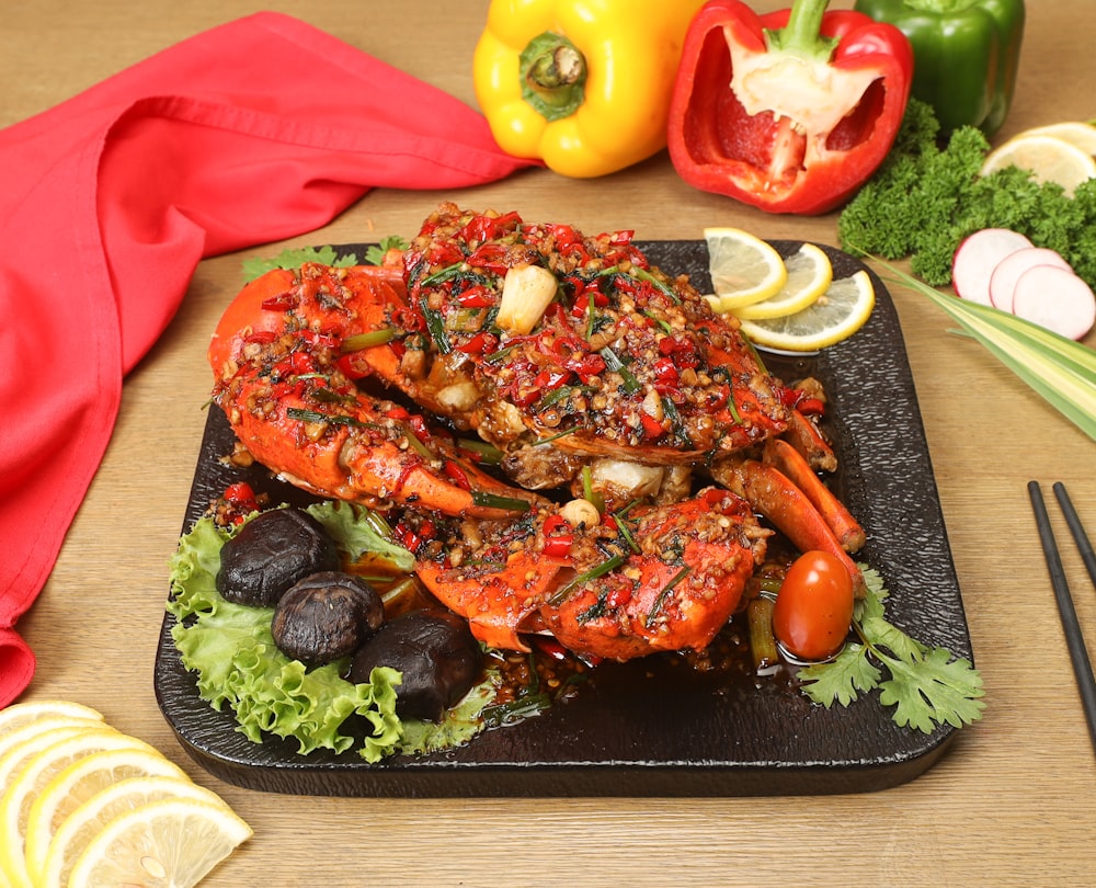 a plate of cooked lobsters and vegetables on a table