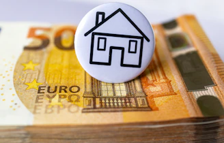 a button with a house on top of a stack of money