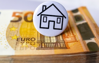 a button with a house on top of a stack of money