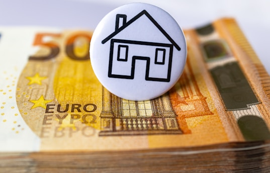 a button with a house on top of a stack of money