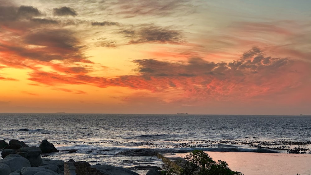 a sunset over the ocean with a boat in the distance