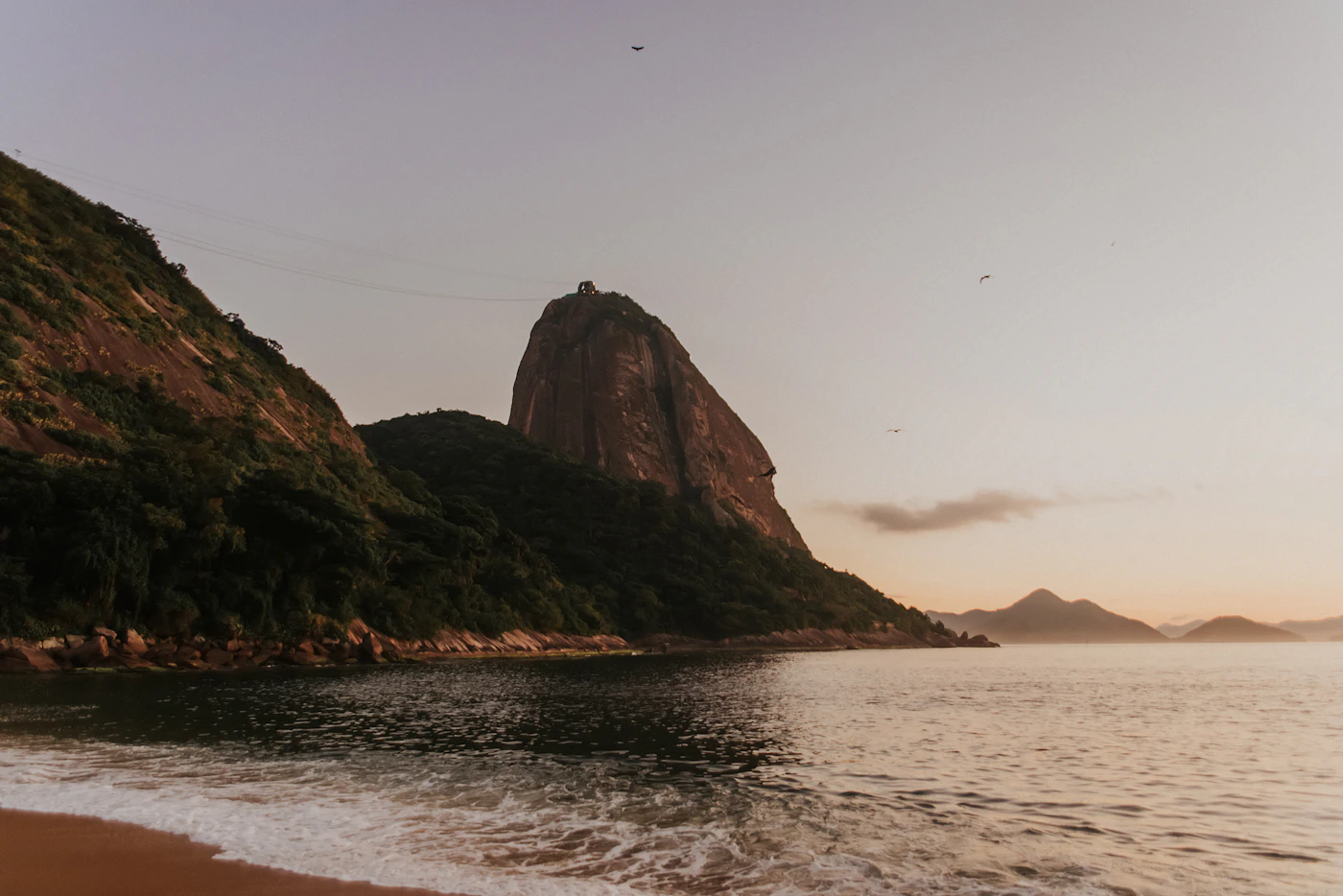 An aerial view of Rio de Janeiro beach and coastline with the distinctive mountains rising from the ocean and the city spreading back from the shore into the valleys between the granite massifs