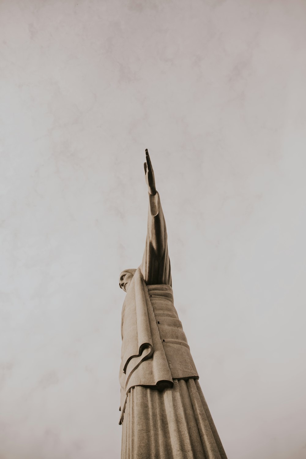 a statue of a person reaching up into the sky