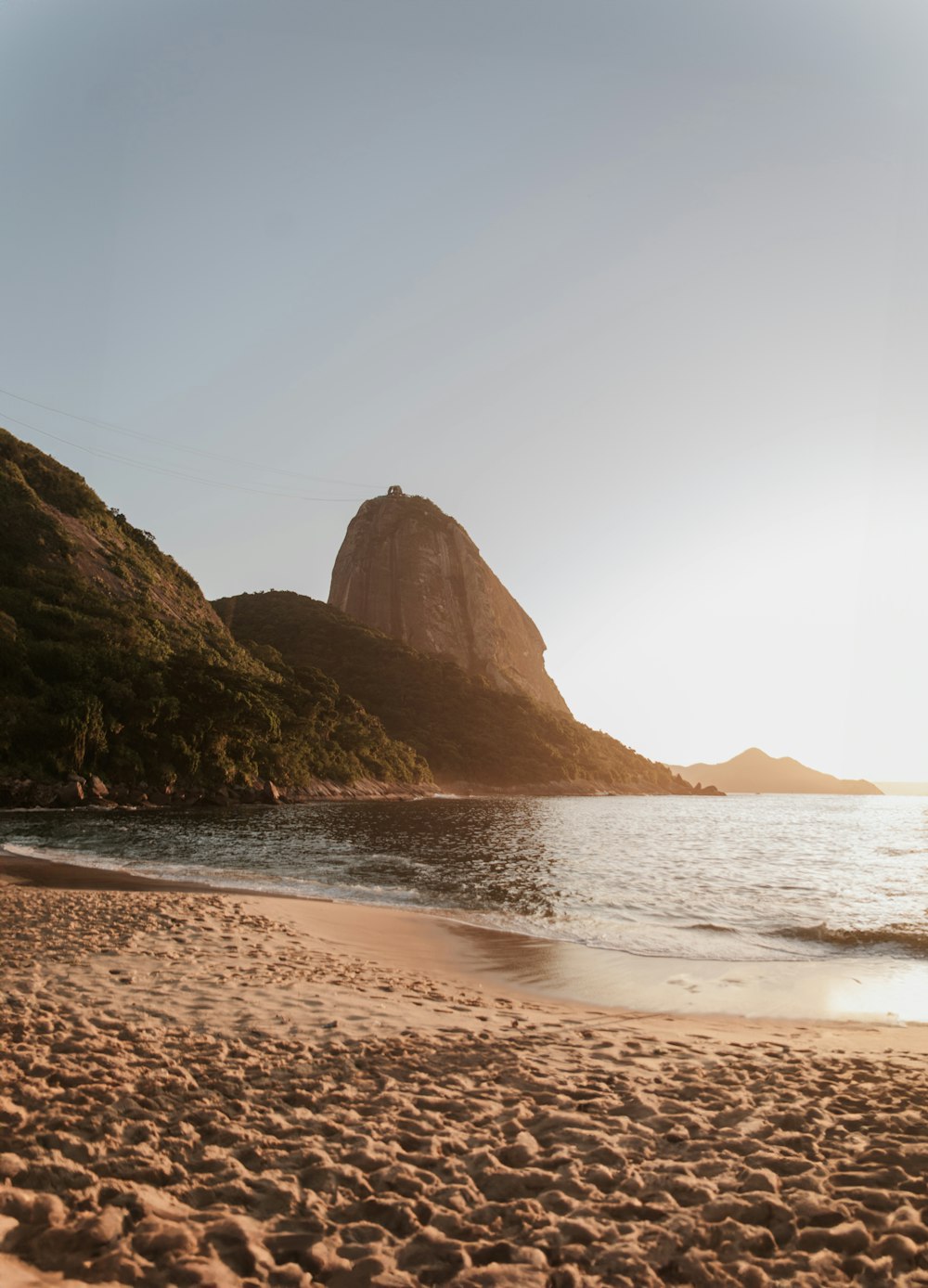 a sandy beach with a mountain in the background