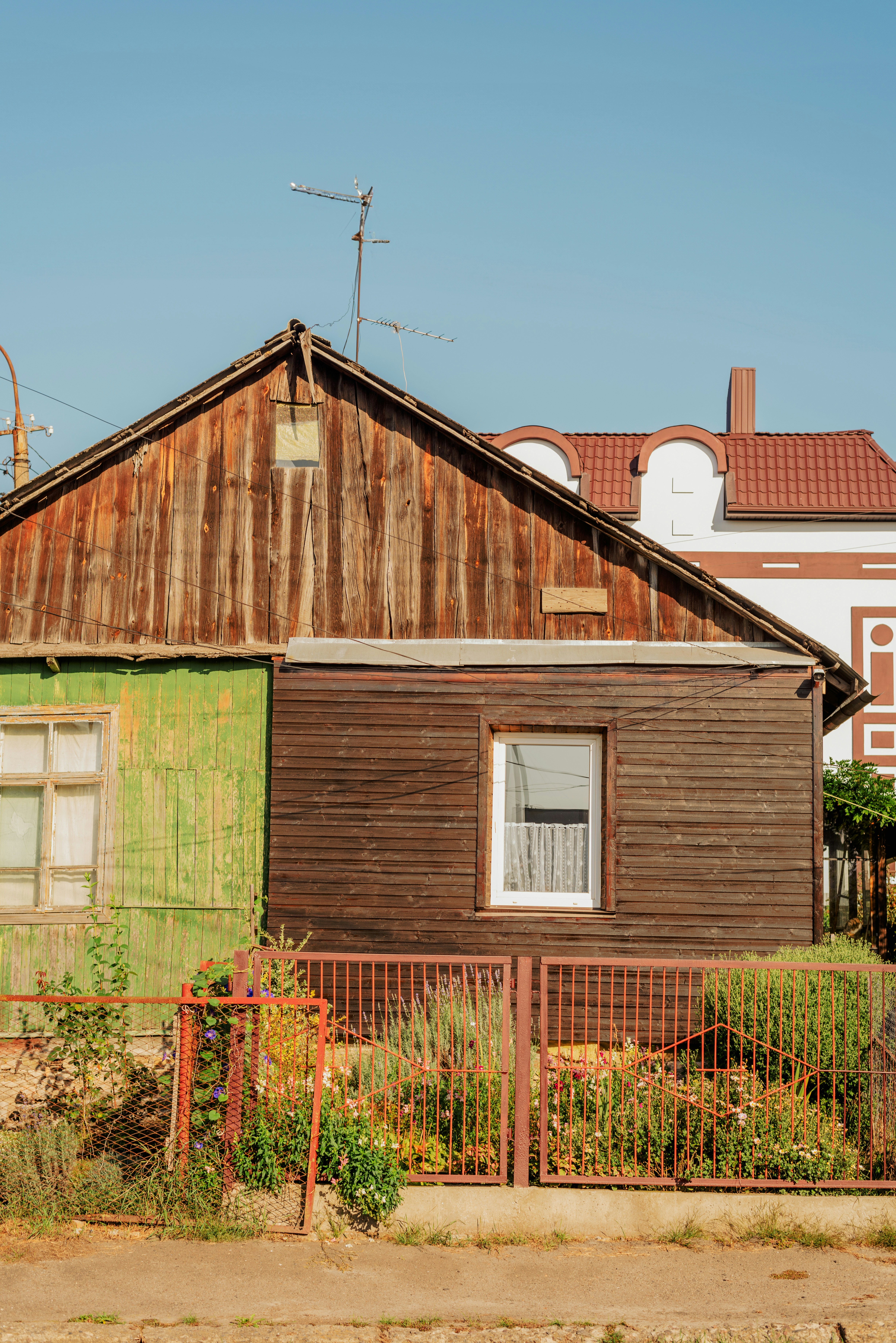 a wooden house with a green door and a red fence