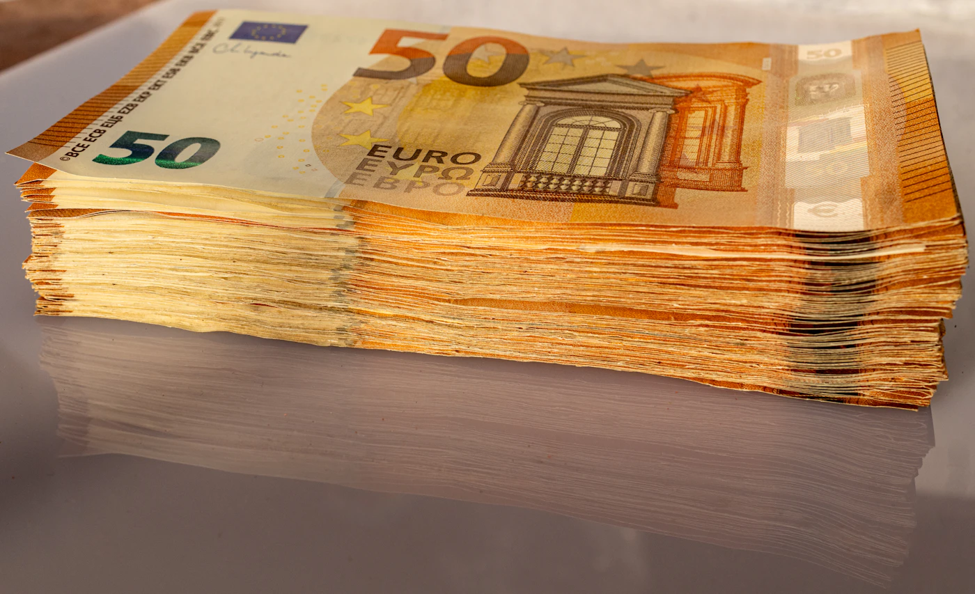 A thick stack of 50 euro banknotes on a reflective table