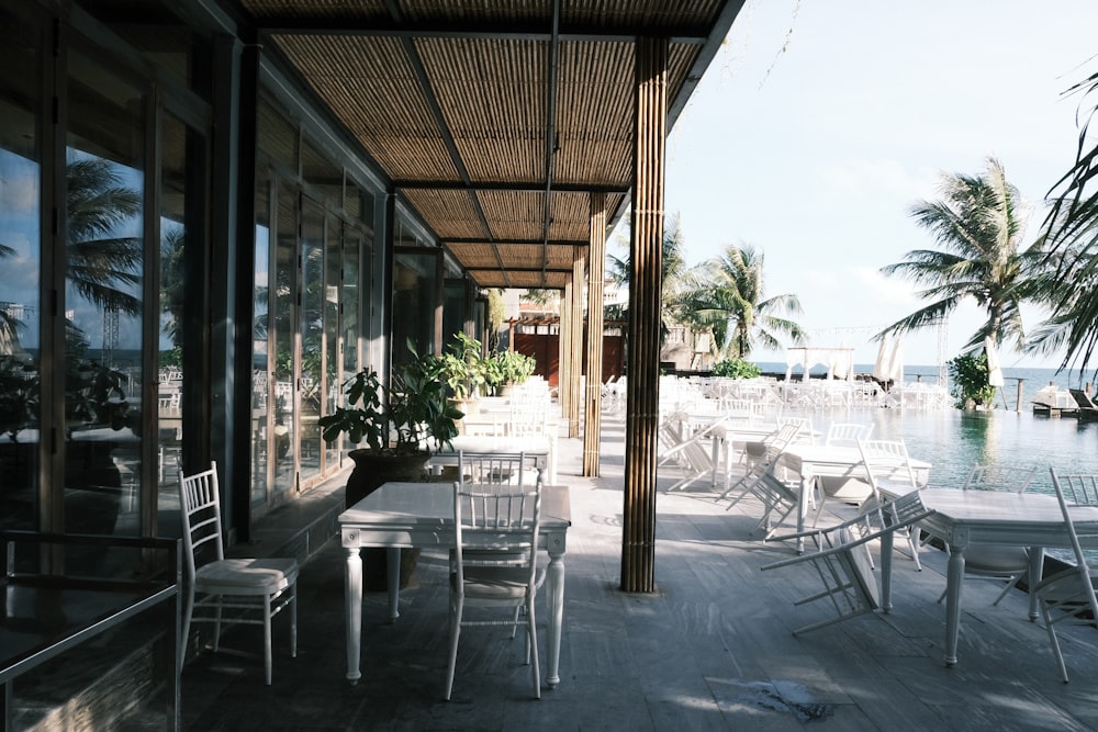 a patio with tables and chairs next to a body of water