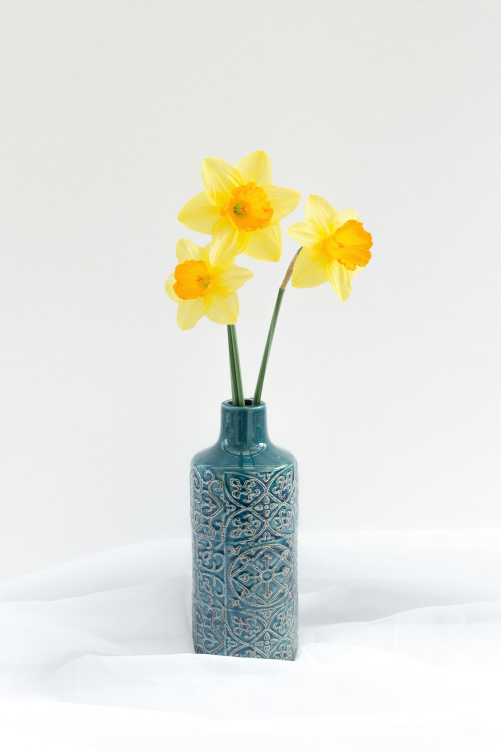 un vase bleu avec des fleurs jaunes à l’intérieur