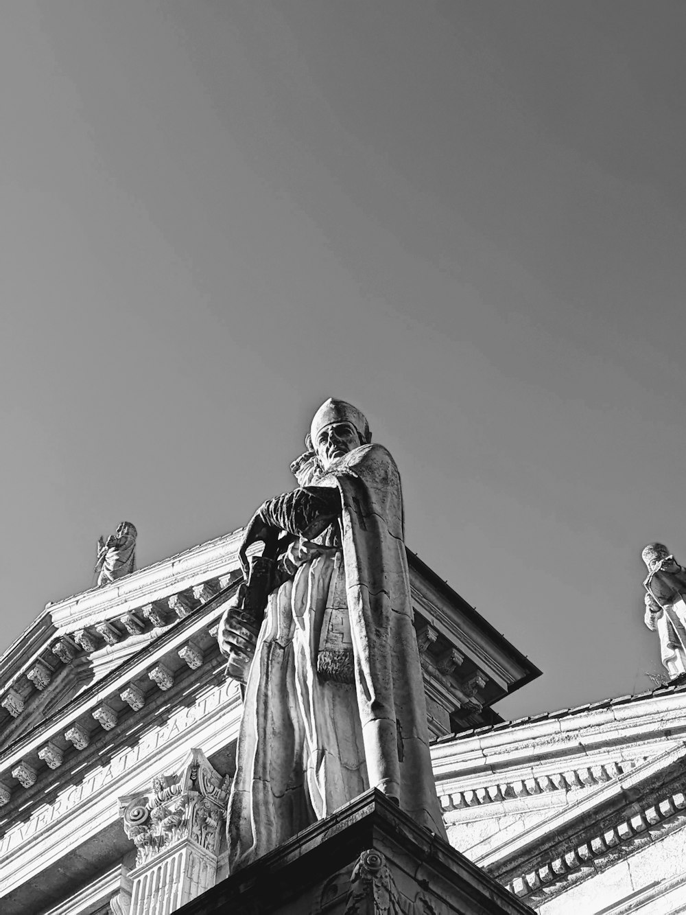 a black and white photo of a statue on top of a building