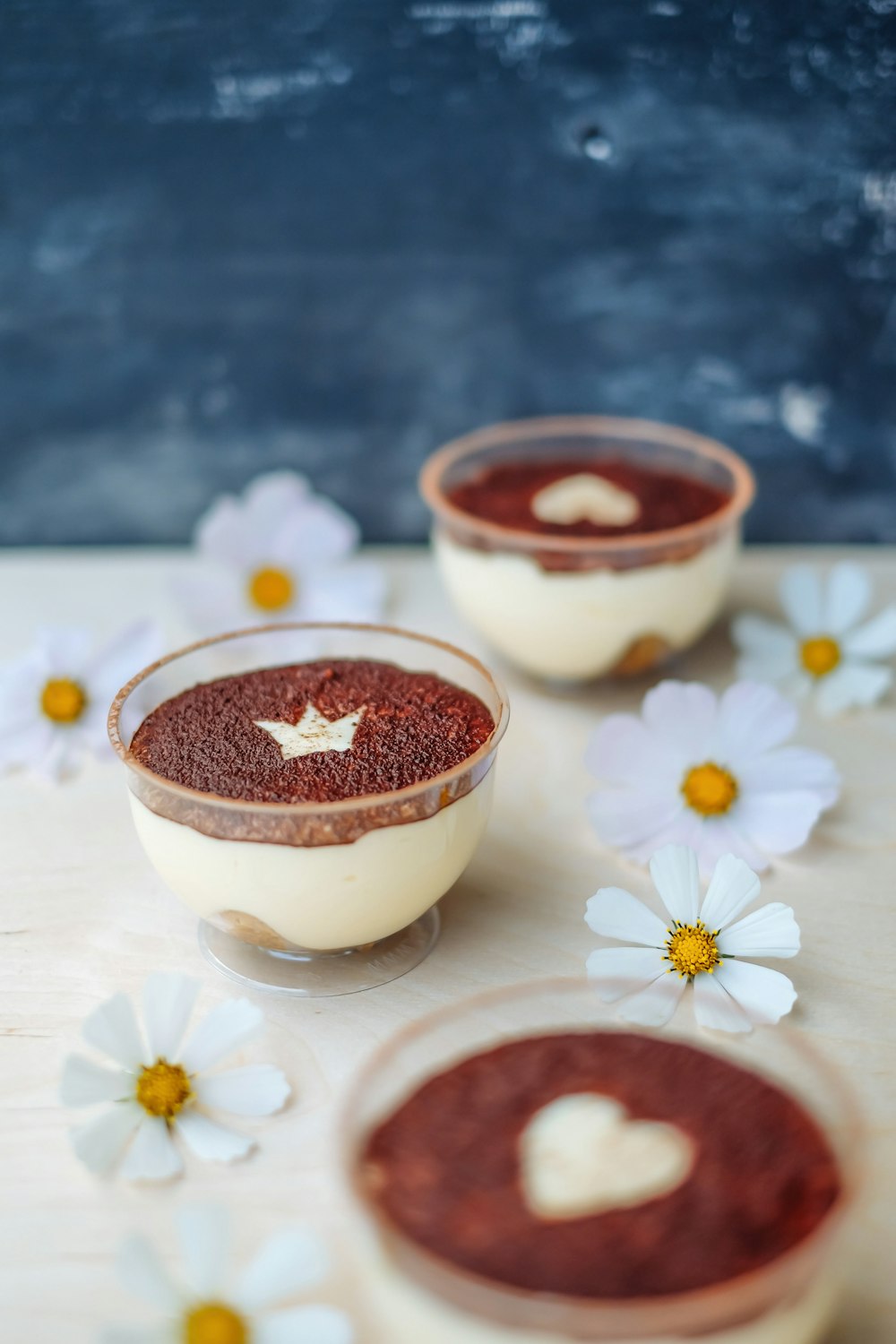 three desserts with chocolate and white flowers on a table