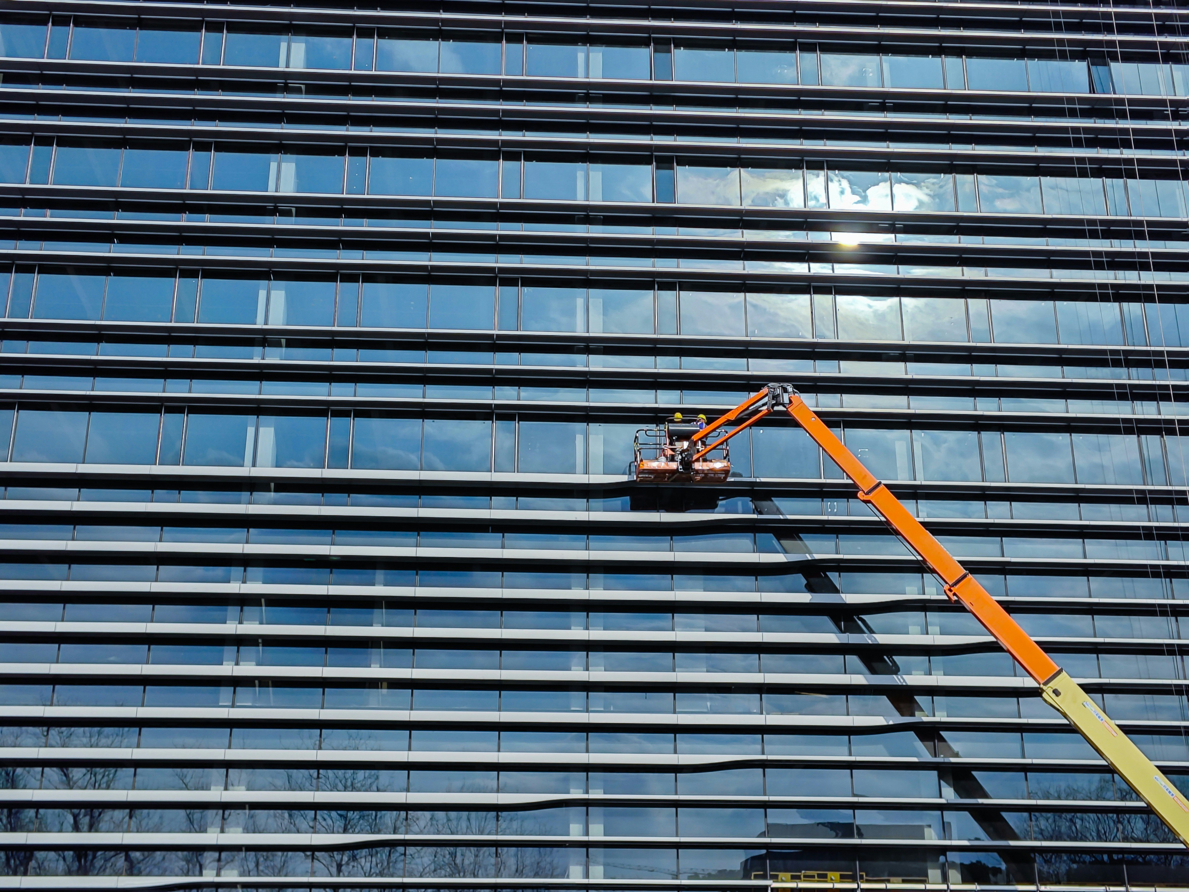 A man on a cherry picker in front of a tall building photo – Free ...