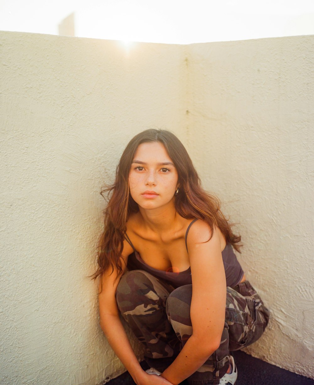 a woman sitting on the ground in front of a wall